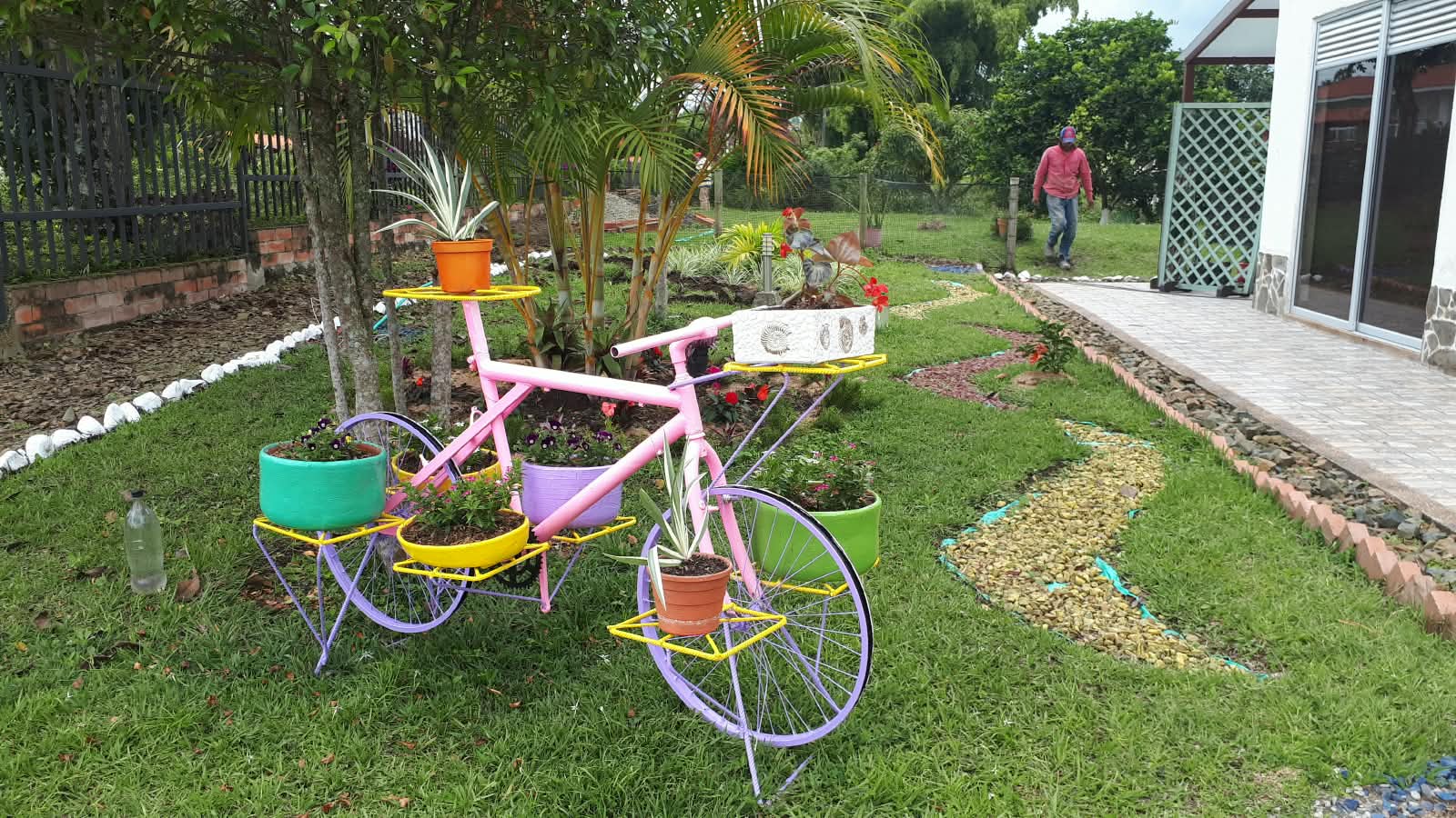 Jardín con bicicleta rosada convertida en matera