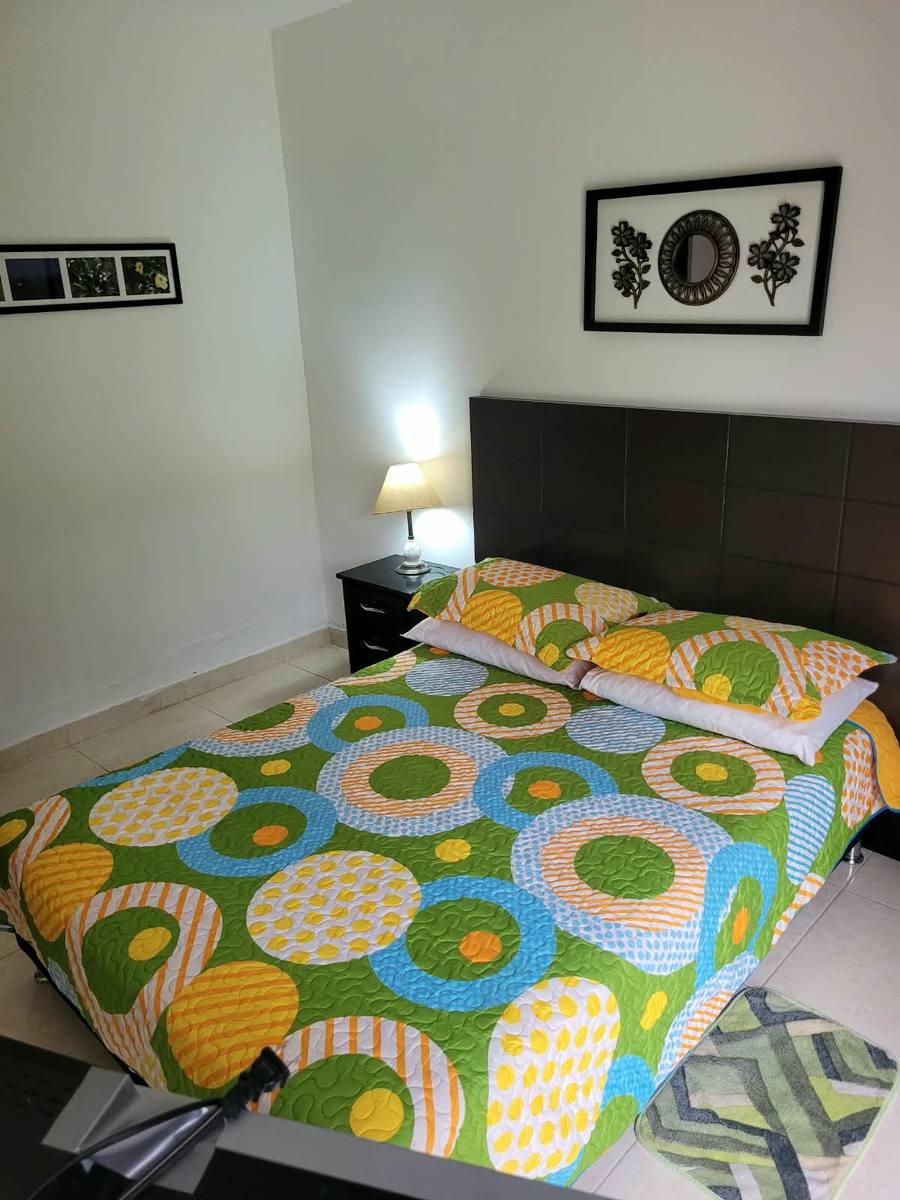 Habitación con cama doble y colcha verde